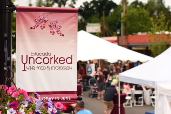 An outdoor event banner for "Estacada Uncorked," promoting wine, food, and microbrew festival.
