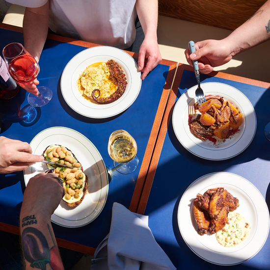 overhead shot of plates of food with hands of diners holding forks