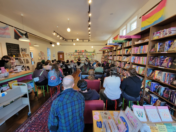 A bookstore event showing an audience seated and facing a speaker at the front of the room.