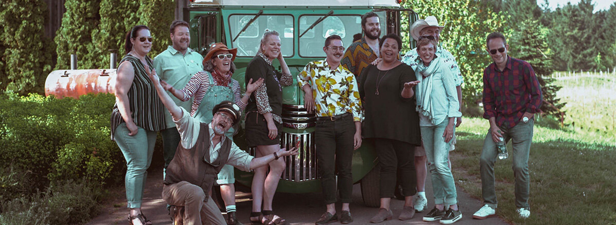 group of people pose in front of vintage bus