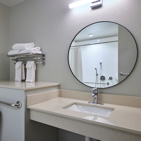 bathroom with circle mirror above sink