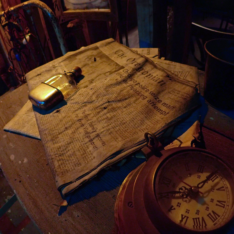 old newspaper with antique bottle on it and clock next to it on a table or crate