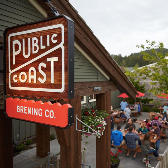 sign for Public Coast Brewing Co. overlooking outdoor patio with diners