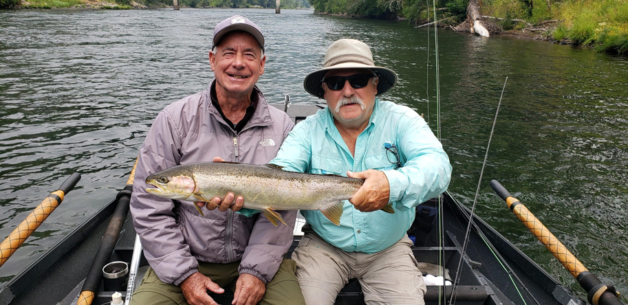 two men in fishing boat, one holds fish