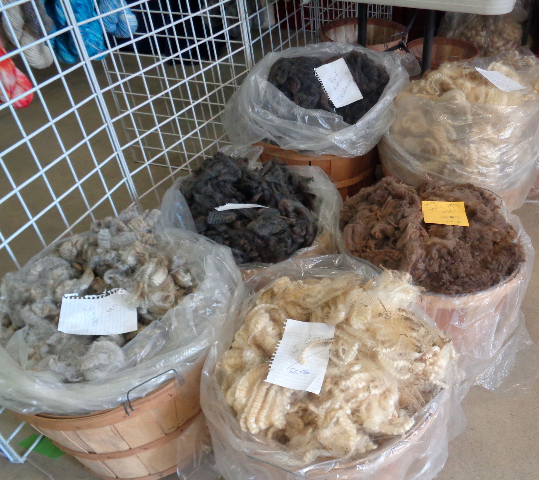 baskets of wool on display in vendor booth of fiber event