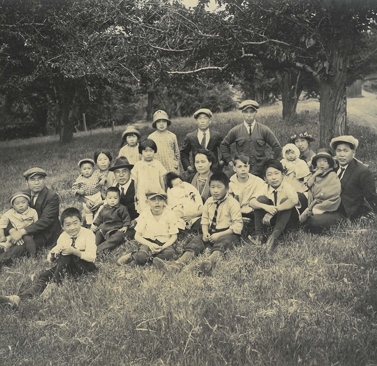 Asian American family and friends seated in the grass