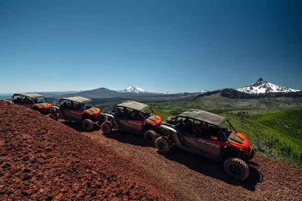 Four ATVs on a path with mountain views in the background