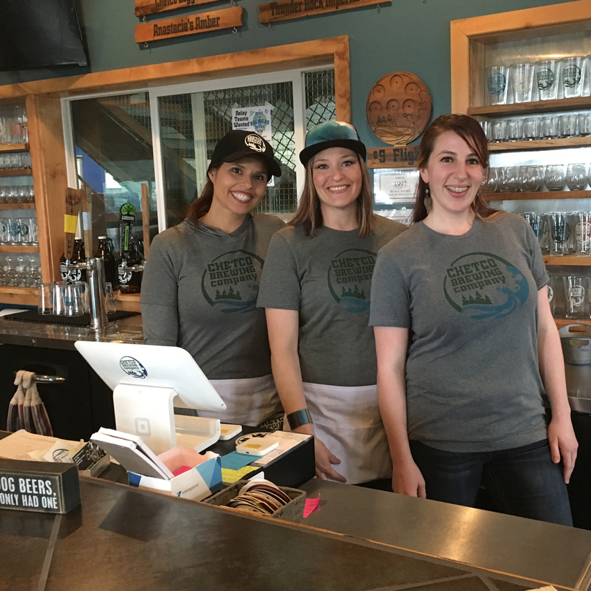 three bartenders pose behind bar