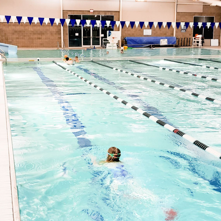 person swimming in lane of indoor pool