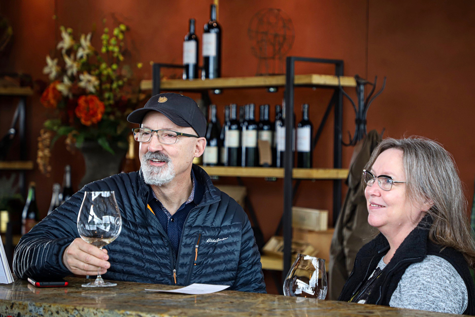 a couple sits at bar for a tasting at a winery