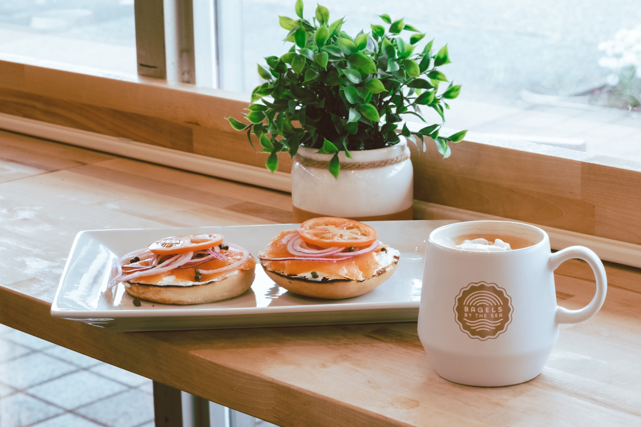 bagels and lox on a plate next to a coffee cup