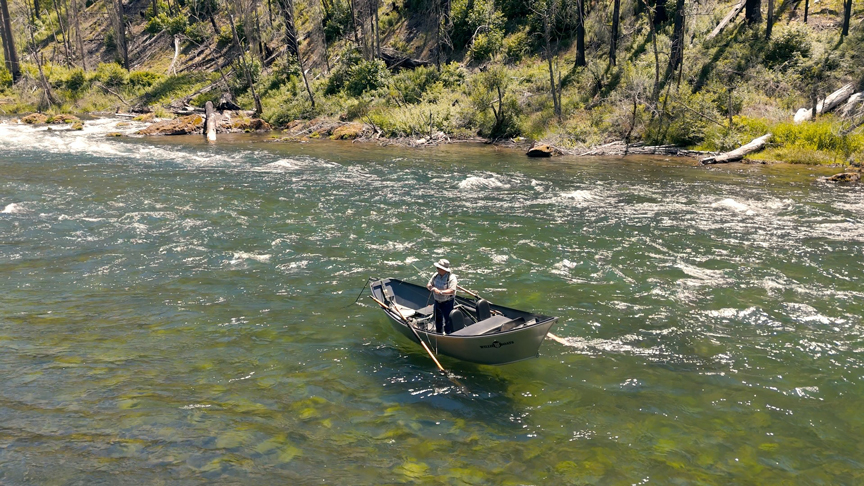 person fishing while standing in a paddle boat