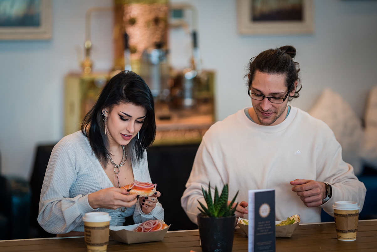 two people sit next to each other while eating bagels