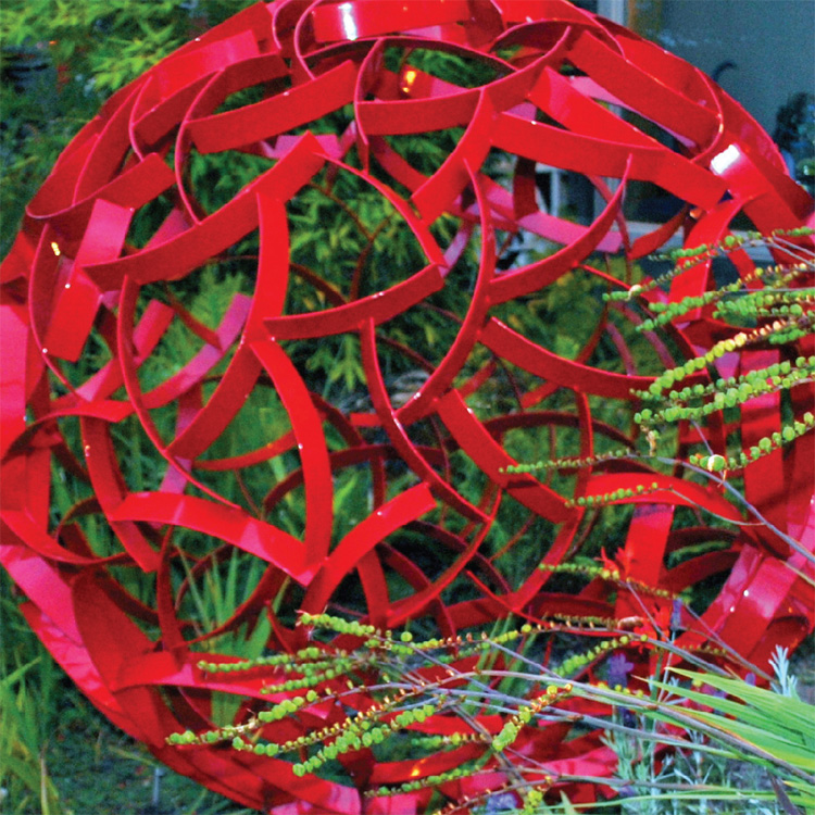 close up of red spherical sculpture in garden