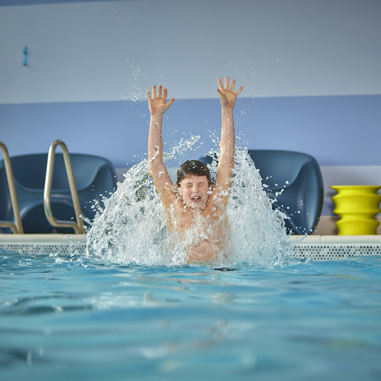 kid in pool with arms raised in the air