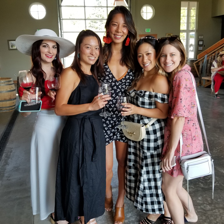 five people posing for photo while wine tasting