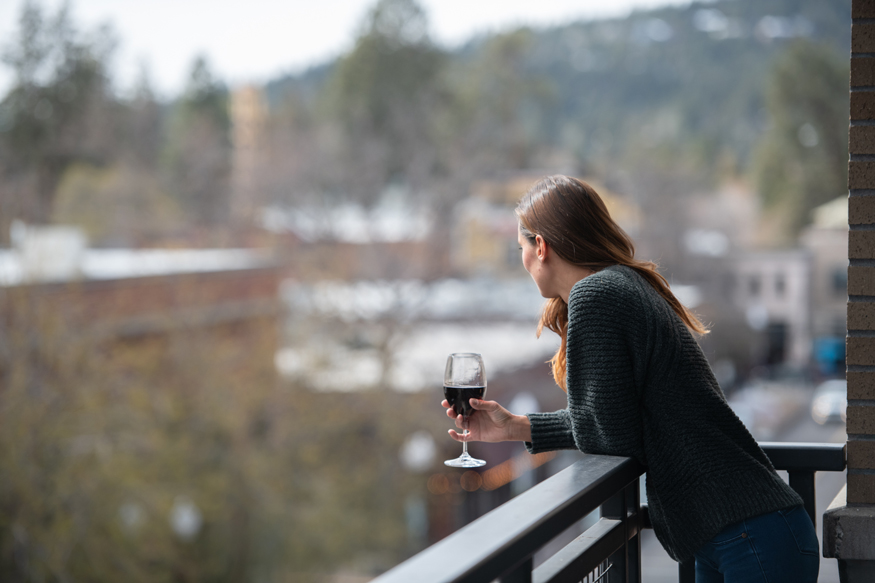 woman holding a wine glass looks out from a balcony