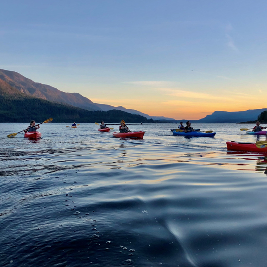 group of kayakers on open water at sunset