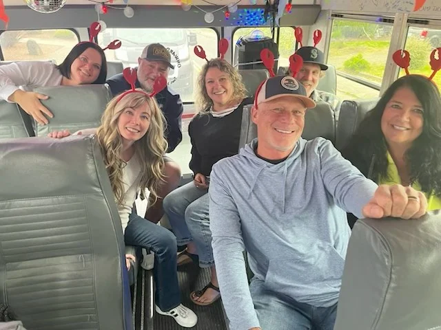 Group wearing crab claw headbands pose on a bus.