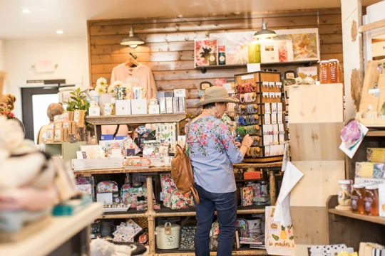 Woman wearing a sunhat perusing jewelry in a gift a shop.