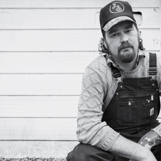 promo photo for musician wearing trucker style cap and overalls