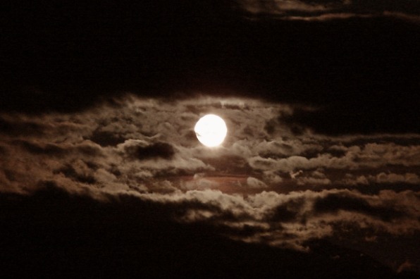 A full moon in a cloudy sky.