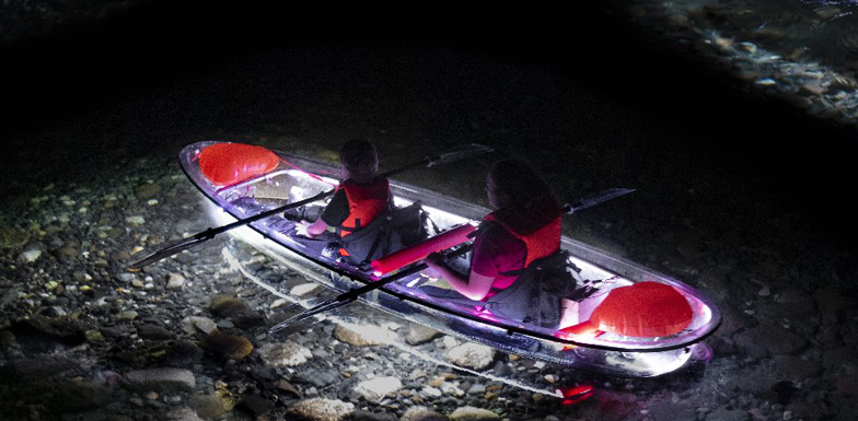 two people in a light up kayak float in lake at night