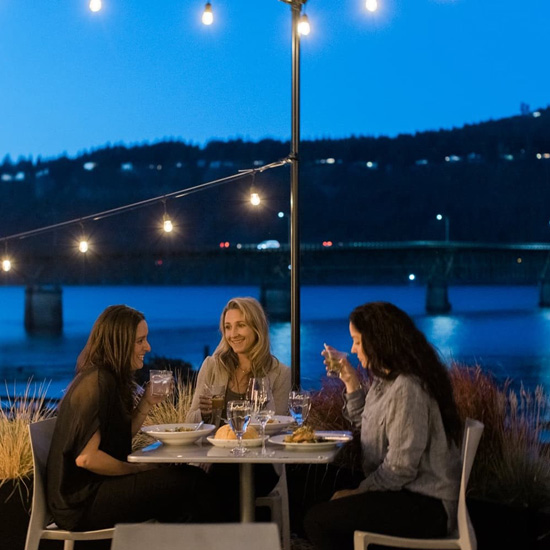 three people dining at table on outdoor patio in the evening