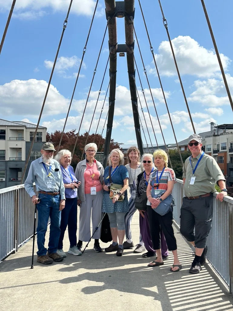 Tour group of eight people stands on a bridge.