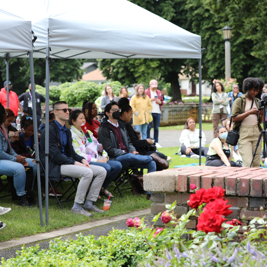 crowd seated under a tent watches a speaker