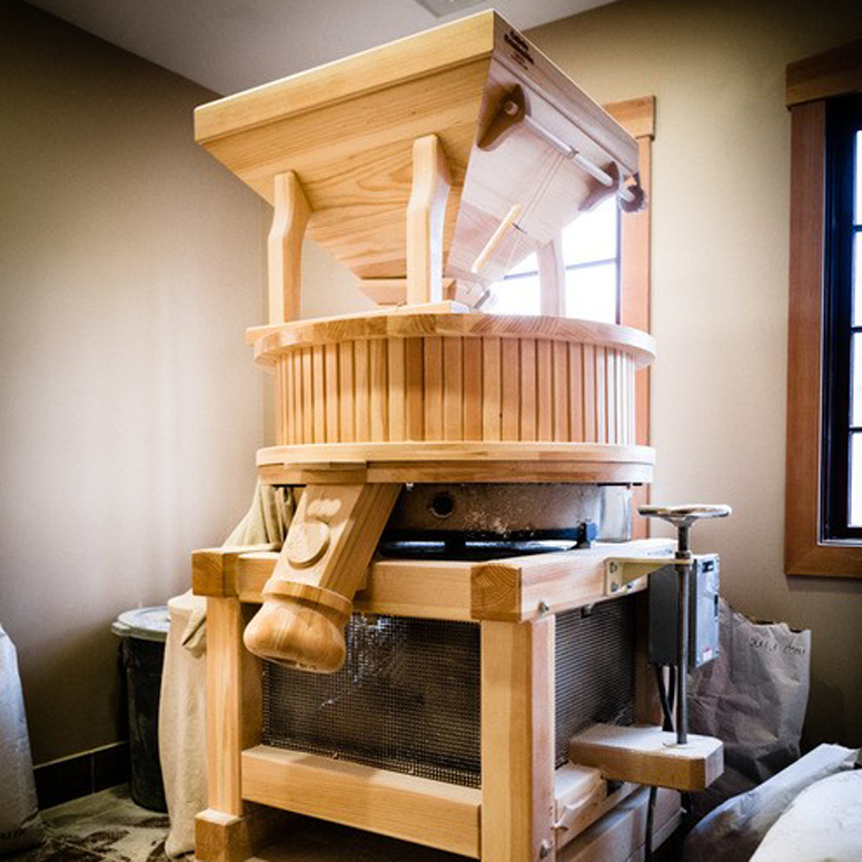 Wooden grain mill in a room.