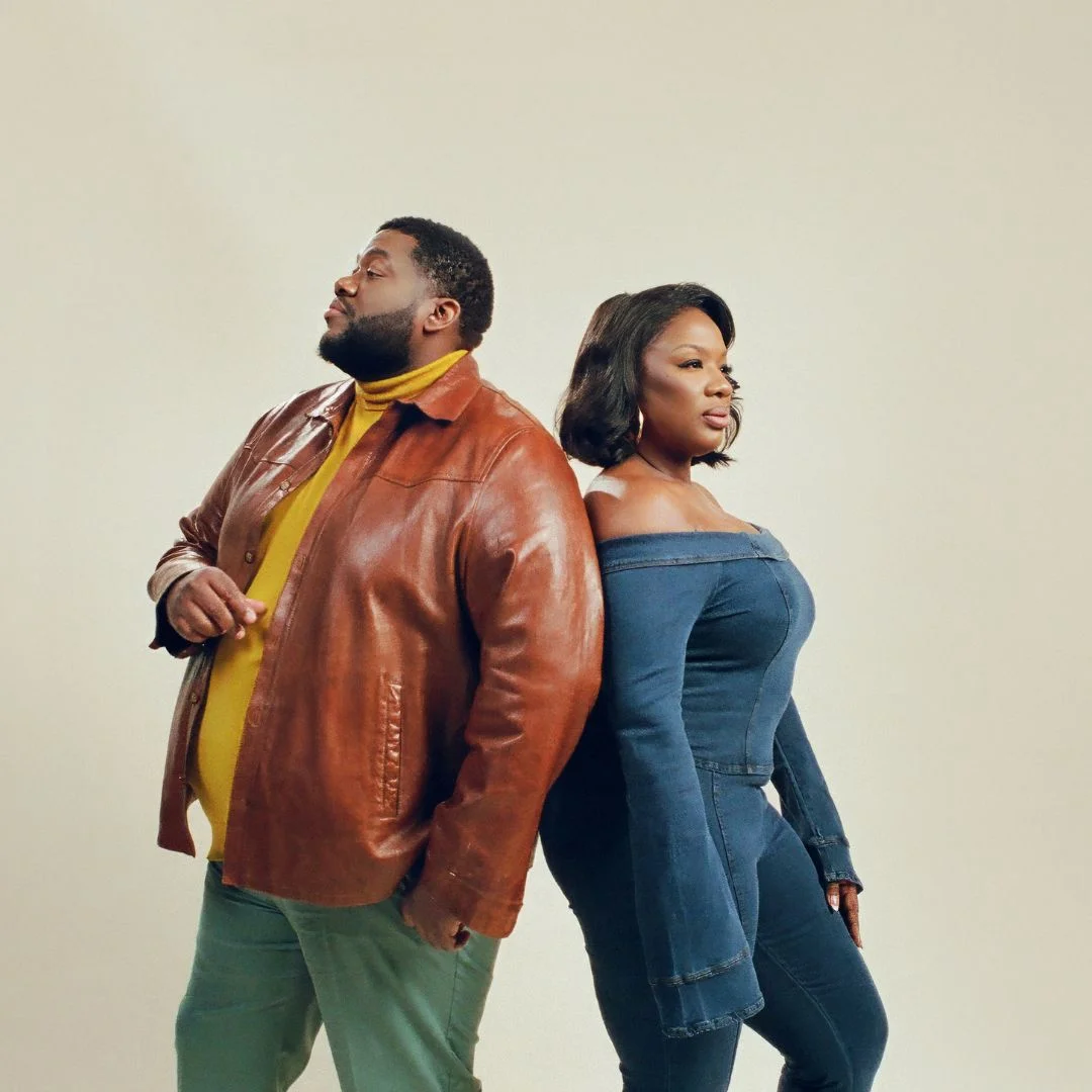 Two people stand with their backs to each other.