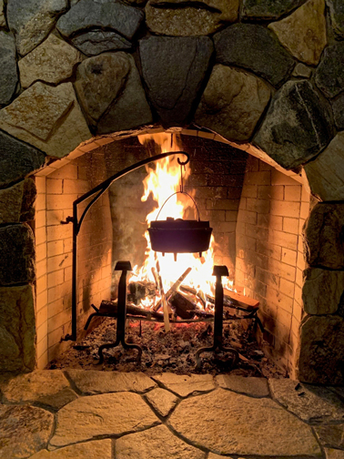 stone fireplace with Dutch oven hanging over the flames