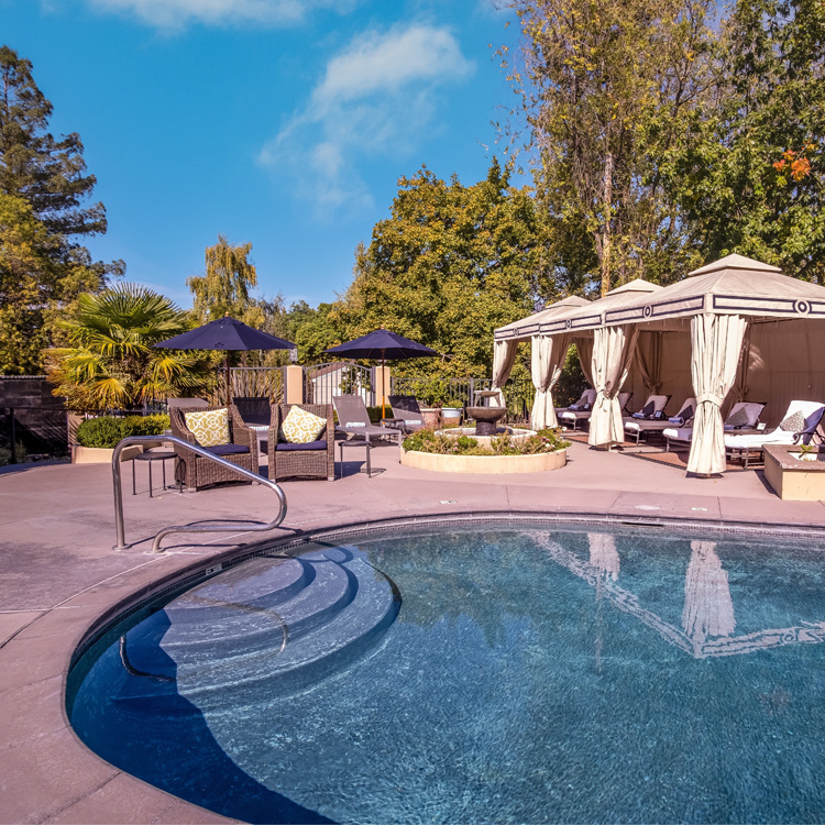 circular pool with patio chairs, umbrellas and lounges near it