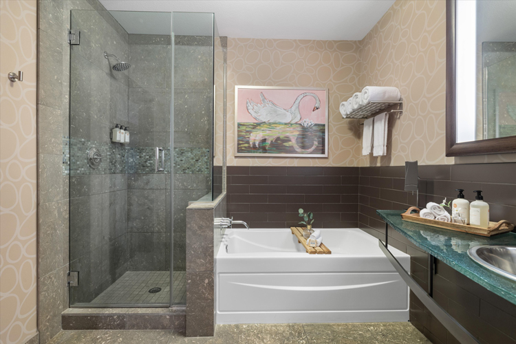 hotel bathroom with bathtub next to walk in shower with painting of a swam on the wall