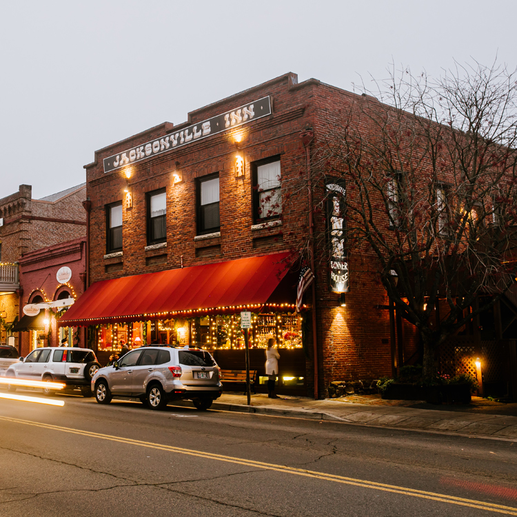 exterior of square brick two story building with awning and lights in first floor windows