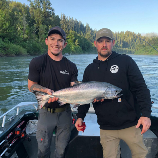 person holds freshly caught fish stands next to boat captain