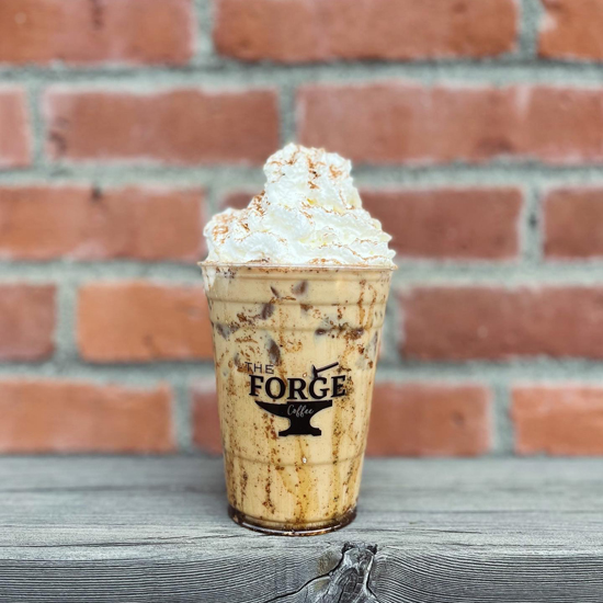 cold espresso beverage topped with whipped cream in to go cup