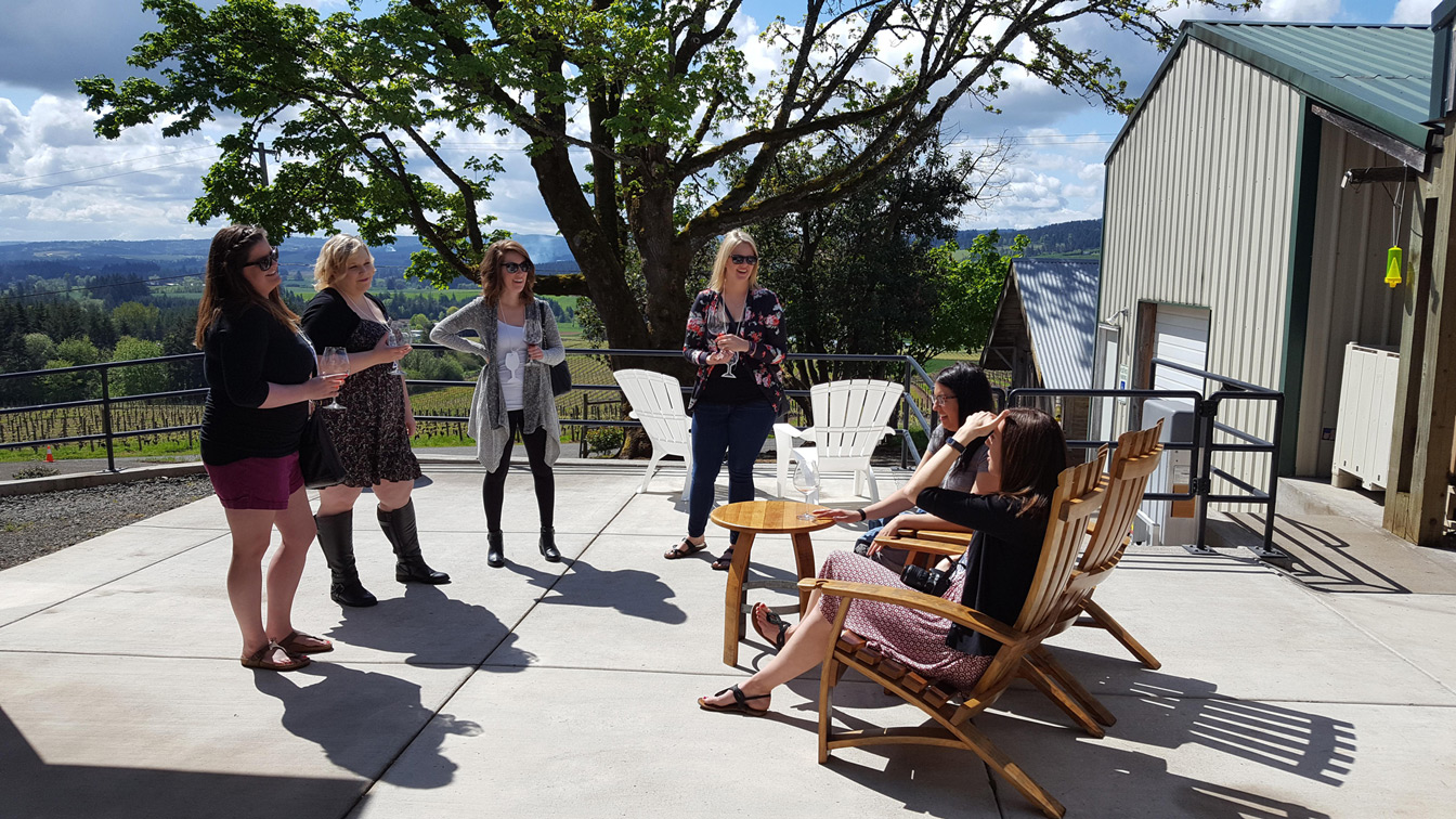 six people laugh on patio of winery