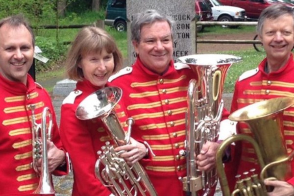 Four people hold their brass instruments.