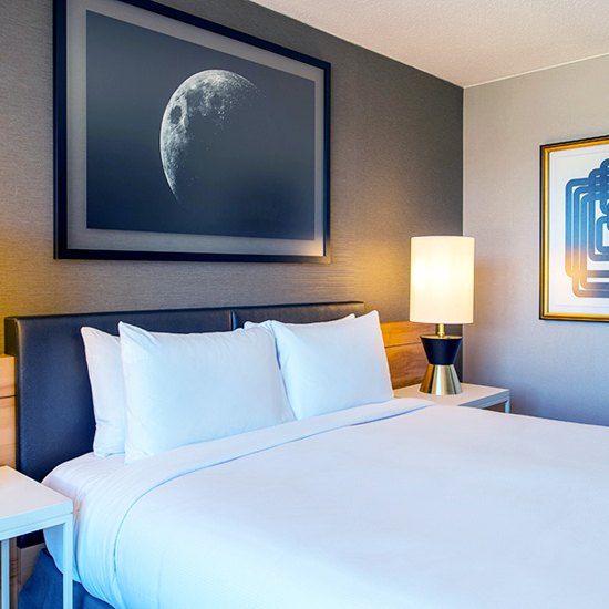 guestroom of hotel with framed art of moon on the wall above headboard of bed