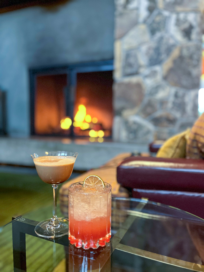 cocktails sit on a side table with fireplace in background