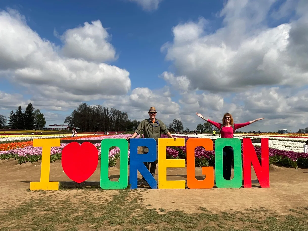 Two people pose behind a cut out sign.