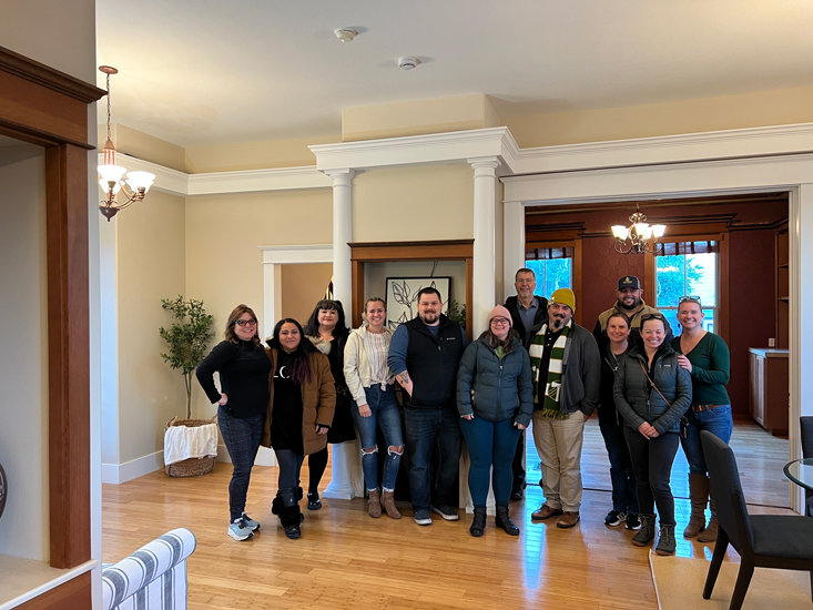group of twelve people pose for photo in large dining room