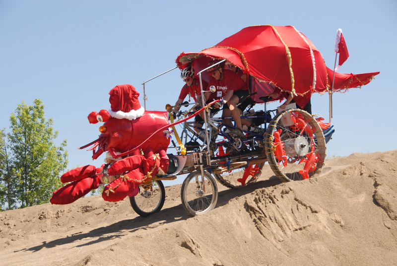 Pedal powered machine decorated as a lobster rolls down a sand dune.