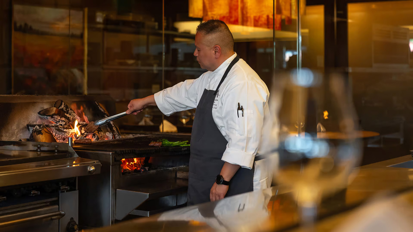 an executive chef attends to woodburning fire