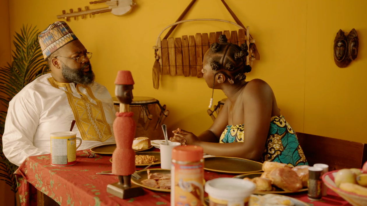 still from film entitled The Bride Price; Two people having a conversation over a meal