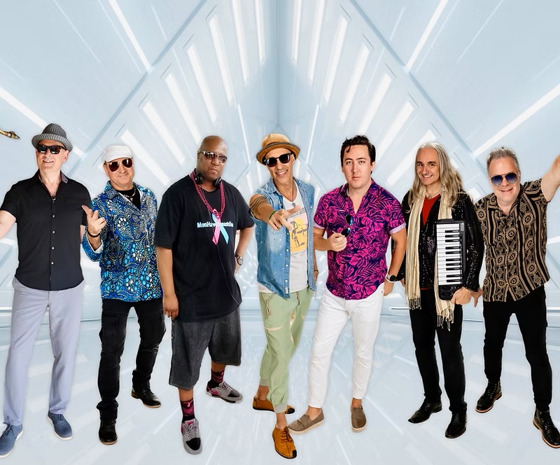 Seven member band faces camera.