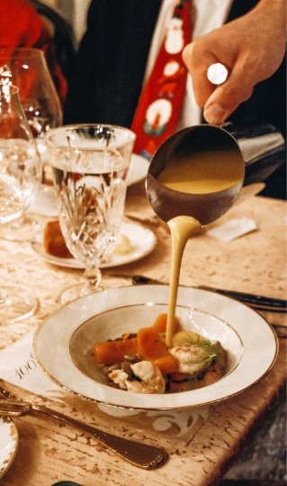 Close up of sauce being poured over vegetables in a shallow bowl.