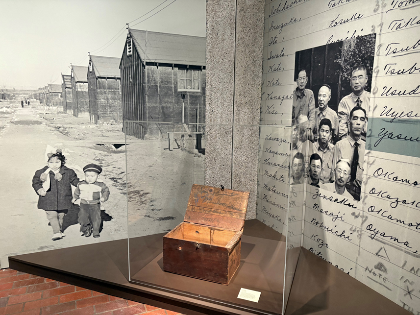museum display of a small wooden trunk behind glass